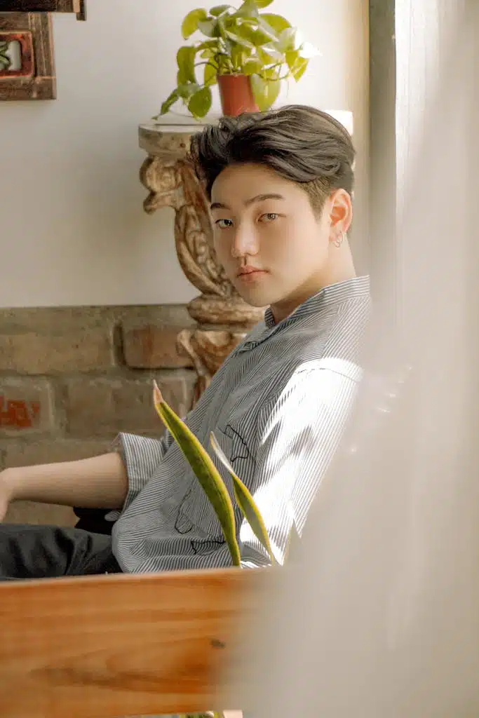 Good-Looking Man in Striped Button-Up Shirt Looking at Camera while Sitting on a Chair