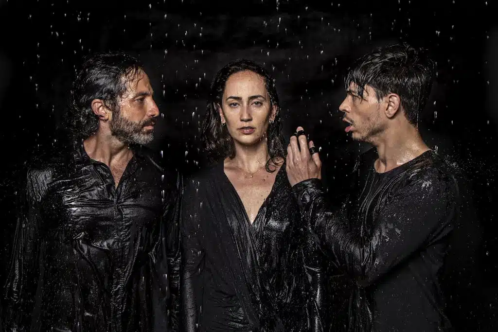Photogenic talented artists wearing wet black clothes standing in studio under water drops