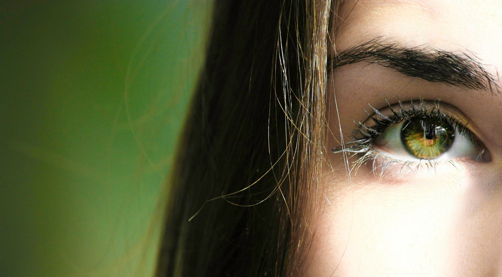 A detailed close-up of a woman's eye with green iris, capturing beauty detail.