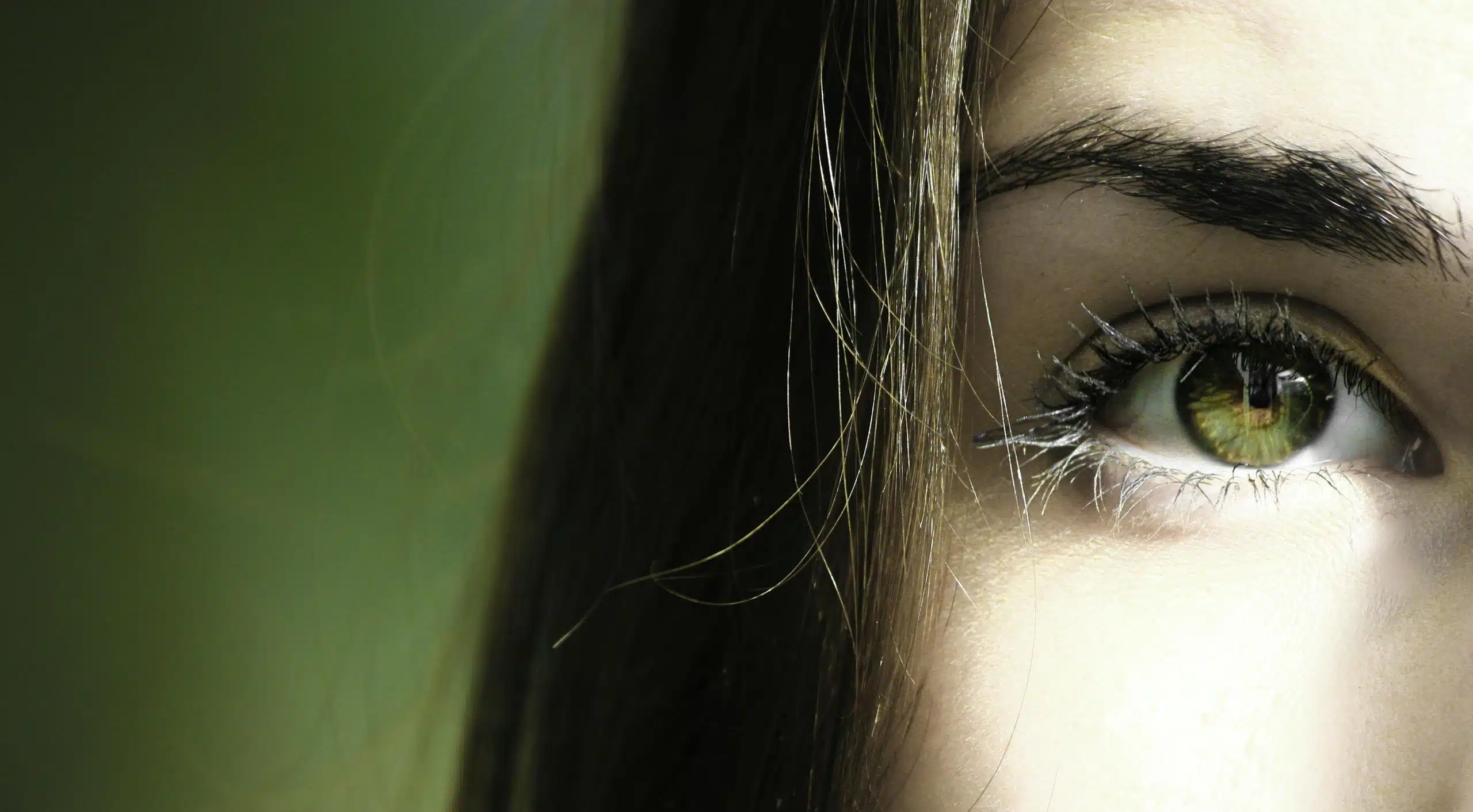 A detailed close-up of a woman's eye with green iris, capturing beauty detail.