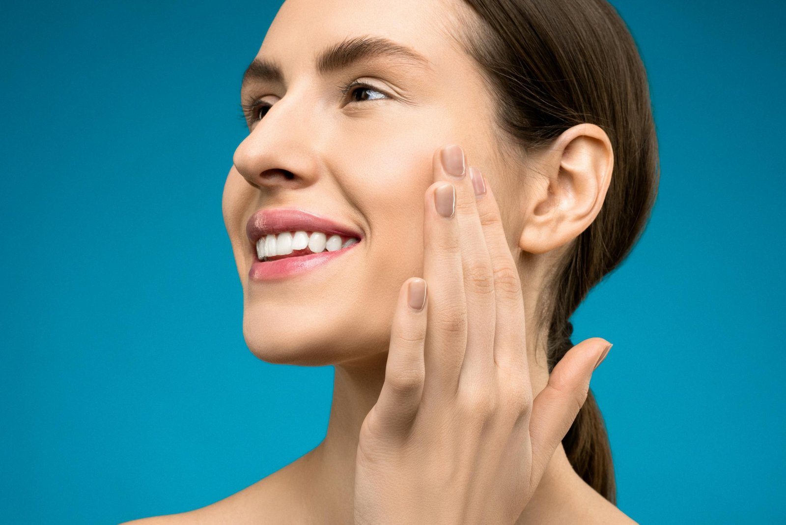 Close-up portrait of a smiling woman with natural makeup, showing confidence and beauty.