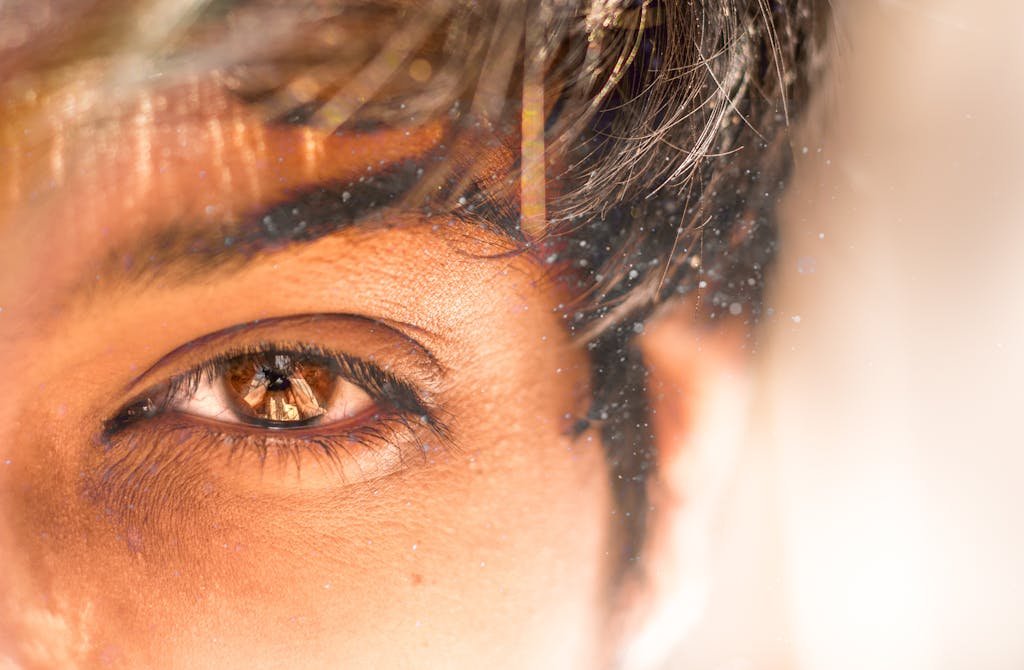 A detailed close-up of a human eye with dust particles reflecting natural light.