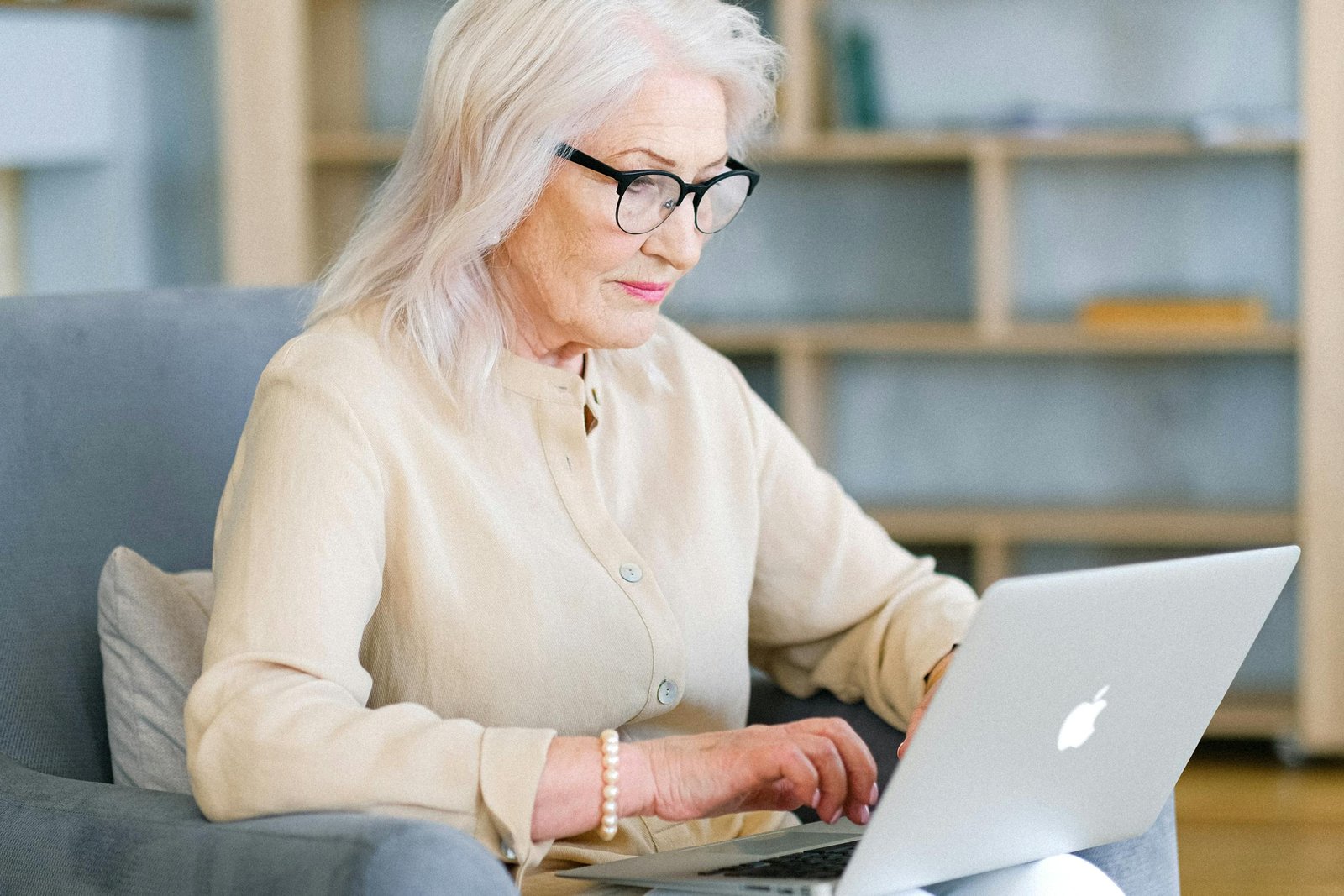 Senior woman sitting indoors using a laptop for online activities.